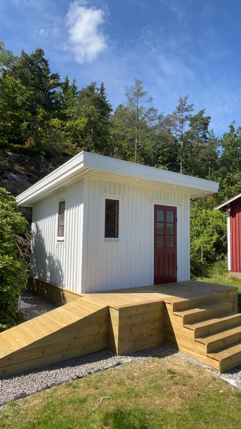 Vit friggebod med altan, trappa och ramp